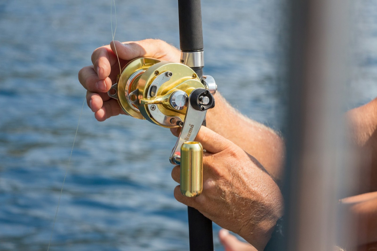 A trolling reel in an angler's hands over open water