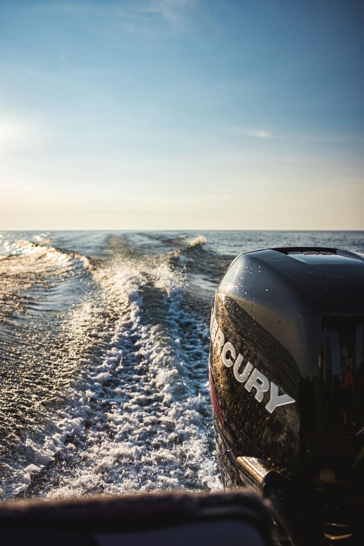 A Mercury outboard over a churning wake at low light
